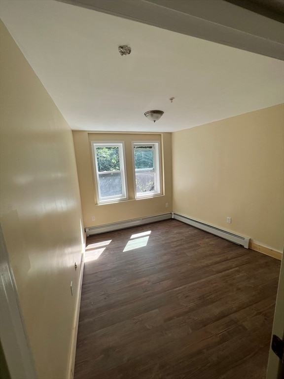 empty room featuring lofted ceiling, a baseboard radiator, and dark wood-type flooring