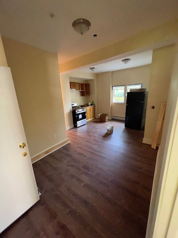 unfurnished living room with dark hardwood / wood-style floors and a baseboard heating unit