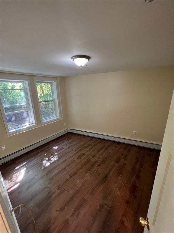 unfurnished room featuring baseboard heating and dark hardwood / wood-style floors