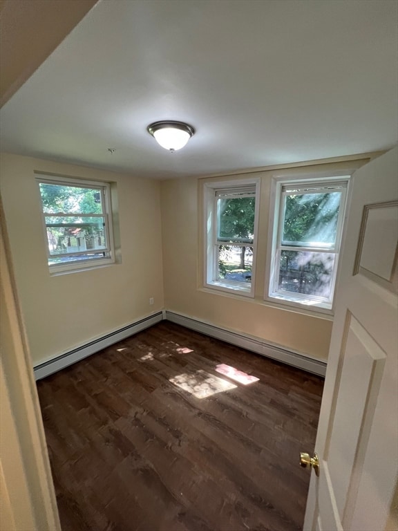 unfurnished room with dark hardwood / wood-style flooring and baseboard heating