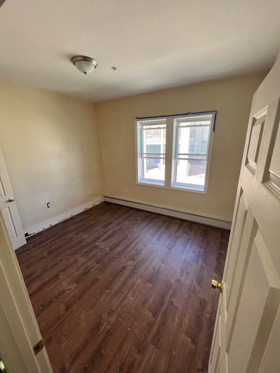 spare room with dark hardwood / wood-style flooring and a baseboard radiator