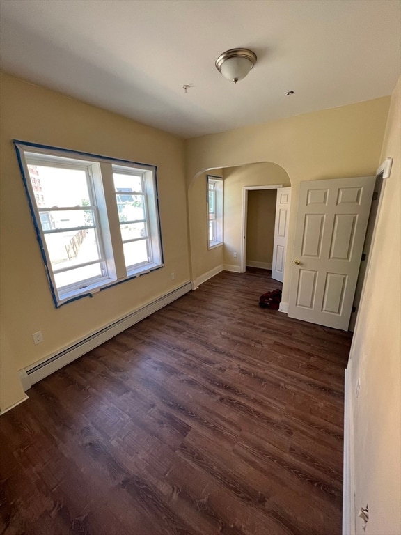 unfurnished room with dark hardwood / wood-style flooring and a baseboard radiator