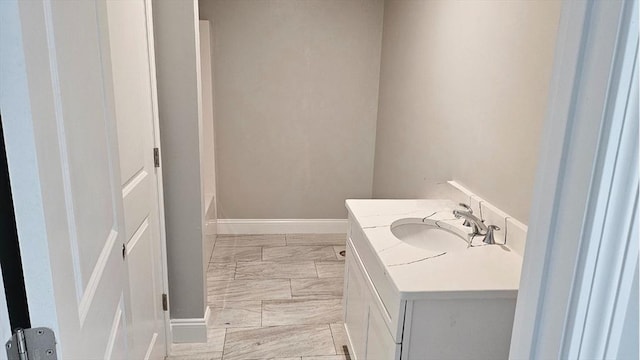 bathroom with a bath, marble finish floor, vanity, and baseboards