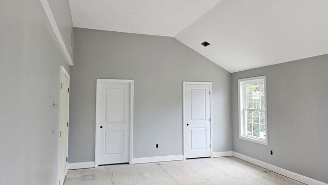 unfurnished bedroom featuring vaulted ceiling, multiple closets, and baseboards