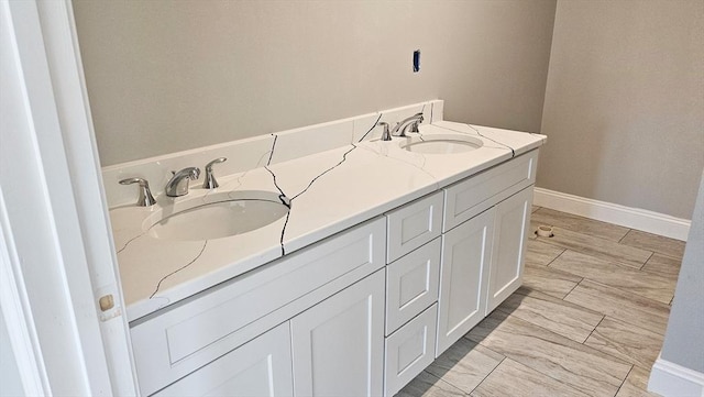 bathroom with double vanity, baseboards, and a sink