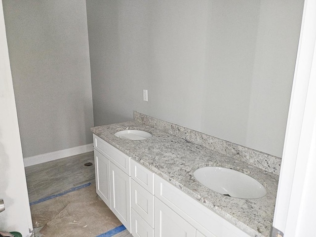 full bathroom with double vanity, baseboards, and a sink