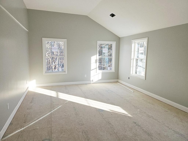 spare room featuring lofted ceiling and baseboards