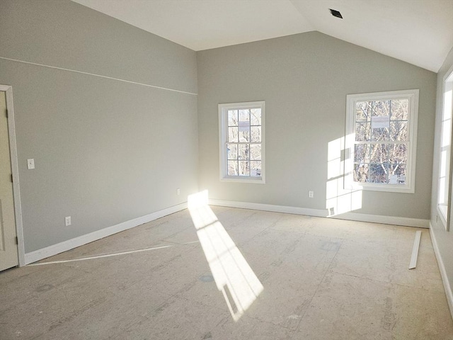 spare room featuring lofted ceiling and baseboards