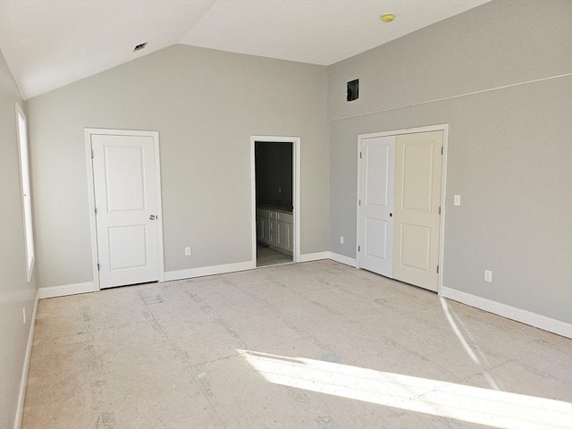 unfurnished bedroom with lofted ceiling, ensuite bath, and baseboards