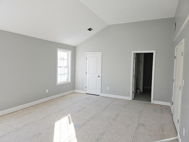 unfurnished bedroom featuring vaulted ceiling, ensuite bath, and baseboards