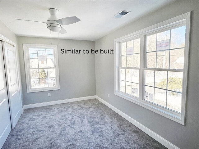 carpeted empty room featuring plenty of natural light, visible vents, and baseboards