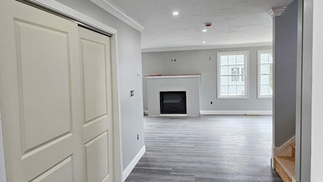 living area featuring a fireplace, crown molding, baseboards, and wood finished floors