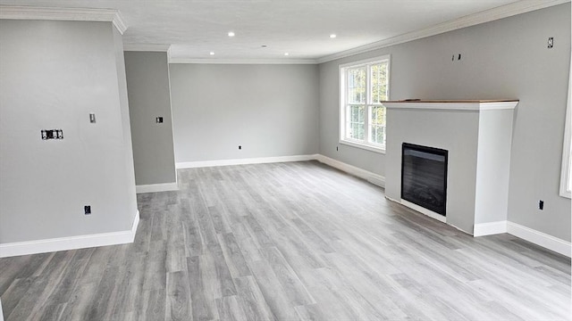 unfurnished living room featuring light wood-style floors, a glass covered fireplace, crown molding, and baseboards