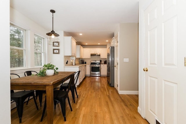 dining area with sink, baseboard heating, and light hardwood / wood-style floors