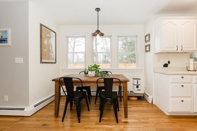 dining room featuring baseboard heating, light hardwood / wood-style flooring, and plenty of natural light