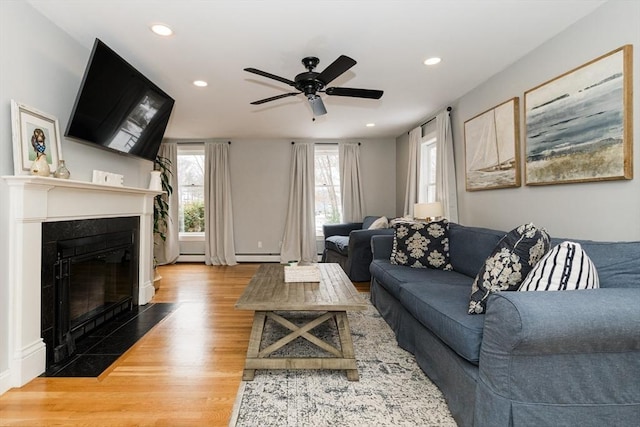 living room with hardwood / wood-style flooring, a baseboard heating unit, ceiling fan, and a wealth of natural light