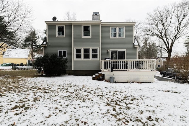 snow covered back of property with a deck