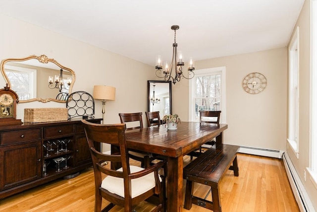 dining area with baseboard heating, light wood-type flooring, and a notable chandelier