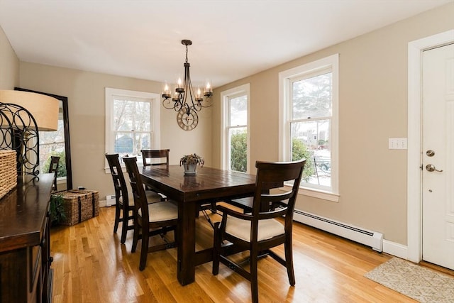 dining room with a baseboard heating unit, light wood-type flooring, a chandelier, and plenty of natural light