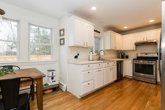 kitchen with appliances with stainless steel finishes, white cabinetry, light wood-type flooring, and sink