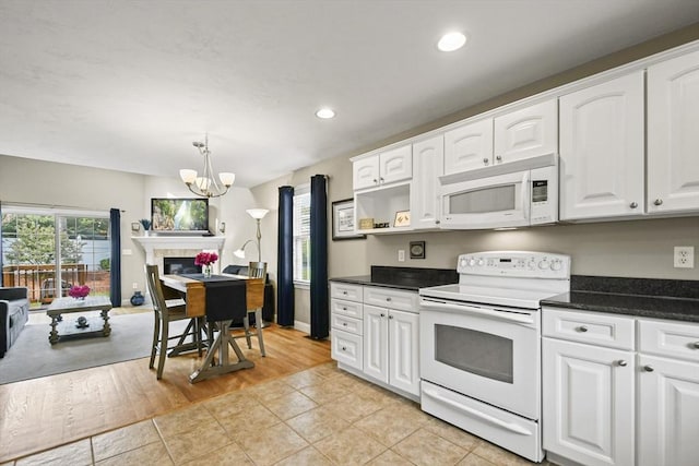 7 Myra Ln Unit 11, Worcester, MA 01606 - kitchen with white appliances, a chandelier, dark countertops, white cabinets, and light tile patterned floors