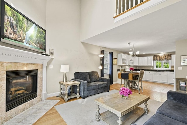 7 Myra Ln Unit 11, Worcester, MA 01606 - living area featuring a fireplace, light wood-type flooring, a high ceiling, a chandelier, and baseboards