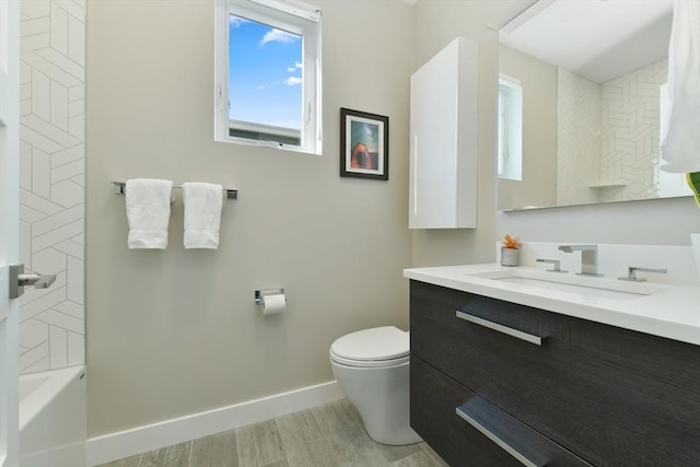 bathroom with toilet, wood finished floors, vanity, baseboards, and tub / shower combination