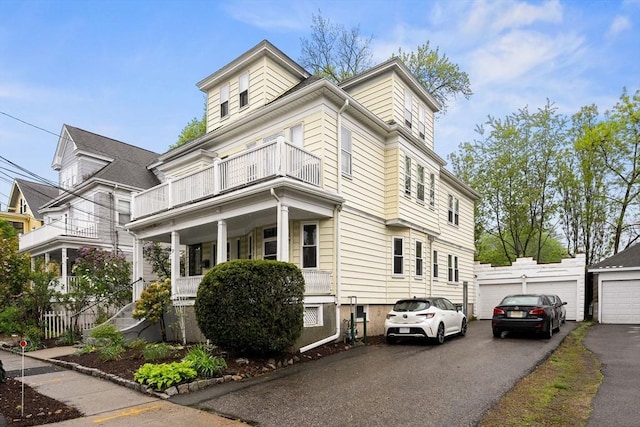 view of front of home with a balcony, a porch, asphalt driveway, and a garage