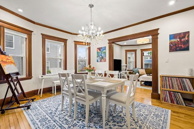 dining space with hardwood / wood-style floors, a chandelier, baseboards, ornamental molding, and recessed lighting