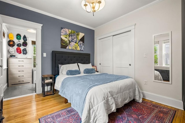 bedroom with wood finished floors, ornamental molding, multiple windows, a closet, and baseboards