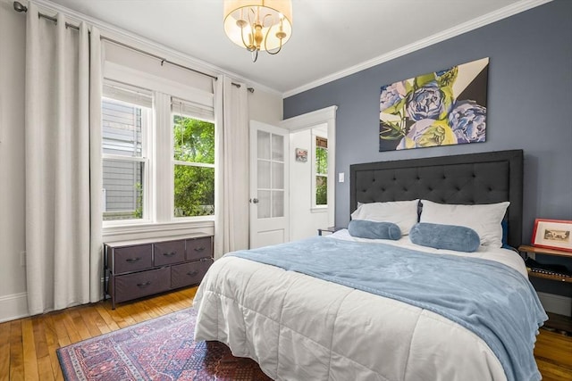 bedroom with hardwood / wood-style floors, crown molding, a chandelier, and baseboards