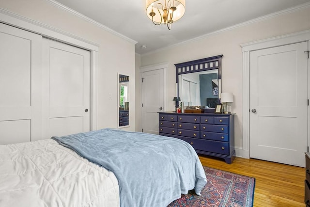 bedroom featuring wood finished floors, a chandelier, crown molding, and a closet