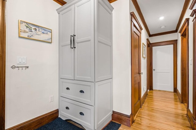 hallway with light wood finished floors, baseboards, and crown molding