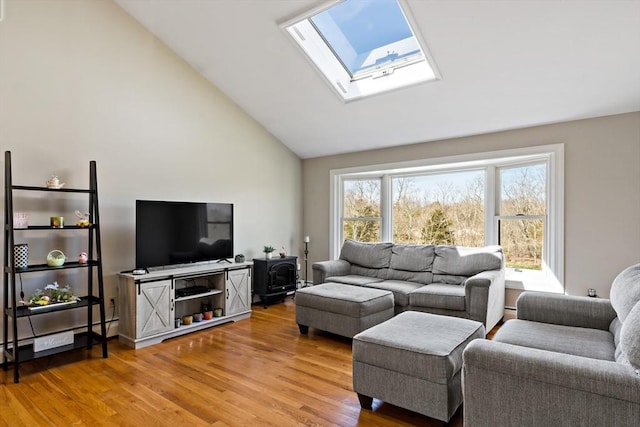living area featuring a skylight, high vaulted ceiling, and light wood-style flooring