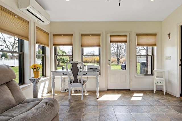 sunroom with stone tile flooring, a wall mounted air conditioner, and baseboards