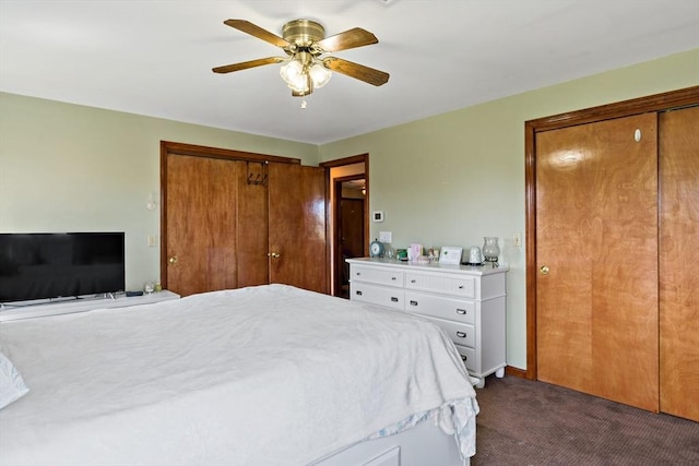 bedroom with dark colored carpet, two closets, and ceiling fan