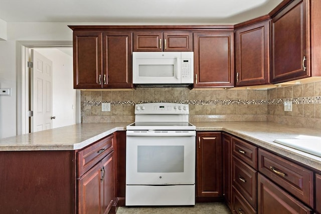 kitchen with reddish brown cabinets, white appliances, decorative backsplash, light countertops, and a peninsula