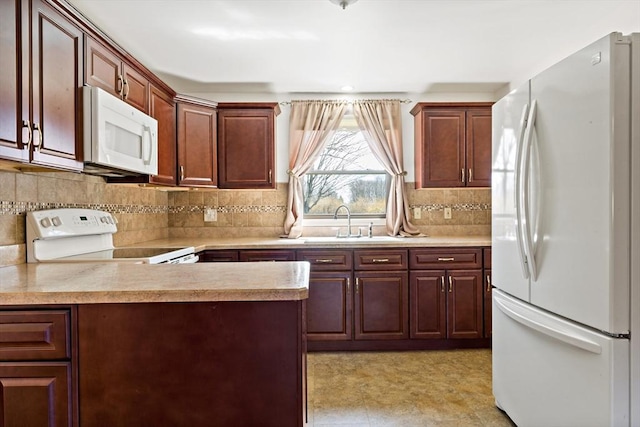 kitchen with tasteful backsplash, white appliances, light countertops, and a sink