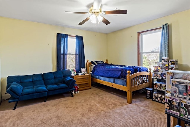 bedroom featuring ceiling fan, multiple windows, and light colored carpet