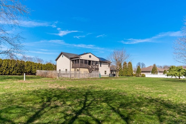 back of property with fence, a yard, and a sunroom