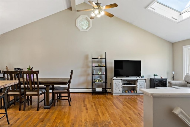 dining room with light wood-style flooring, ceiling fan, high vaulted ceiling, and a skylight