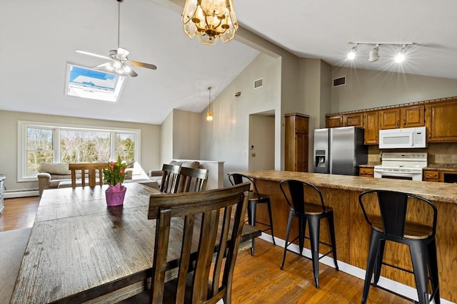 kitchen with wood finished floors, white appliances, rail lighting, brown cabinets, and visible vents