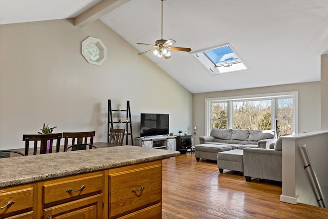 living area featuring a skylight, wood finished floors, ceiling fan, beam ceiling, and high vaulted ceiling