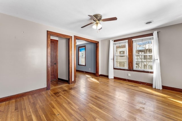 unfurnished room with visible vents, baseboards, ceiling fan, and wood finished floors