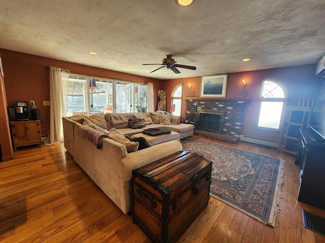 living room with hardwood / wood-style flooring, a fireplace, visible vents, and a textured ceiling