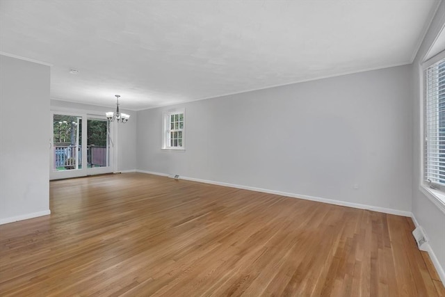 unfurnished room with a chandelier, light wood-style flooring, baseboards, and ornamental molding
