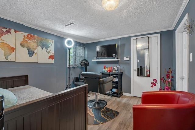 bedroom featuring wood finished floors, ornamental molding, a textured ceiling, and baseboards