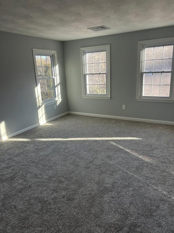 unfurnished room featuring carpet flooring, plenty of natural light, visible vents, and baseboards