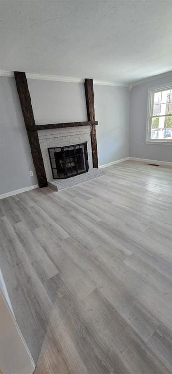 unfurnished living room featuring a brick fireplace, baseboards, wood finished floors, and ornamental molding