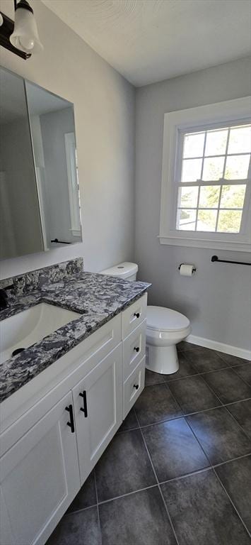 bathroom with toilet, baseboards, vanity, and tile patterned floors